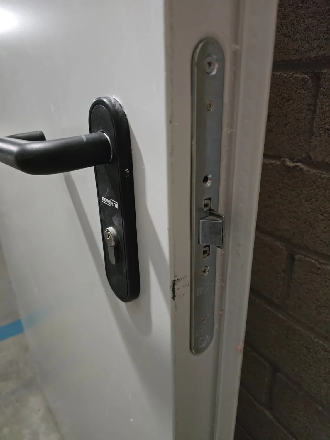 Manilla negra y mecanismo en una puerta metálica abierta